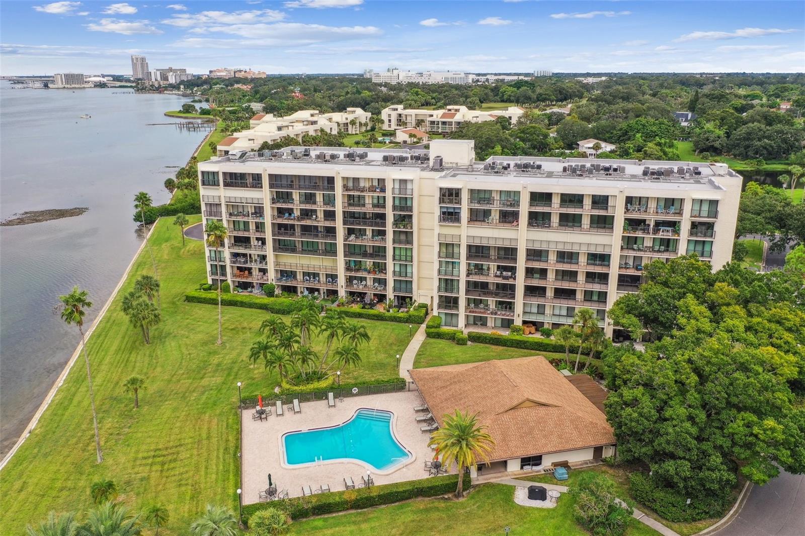 Waterfront condominium complex with a landscaped lawn and swimming pool beside the bay.