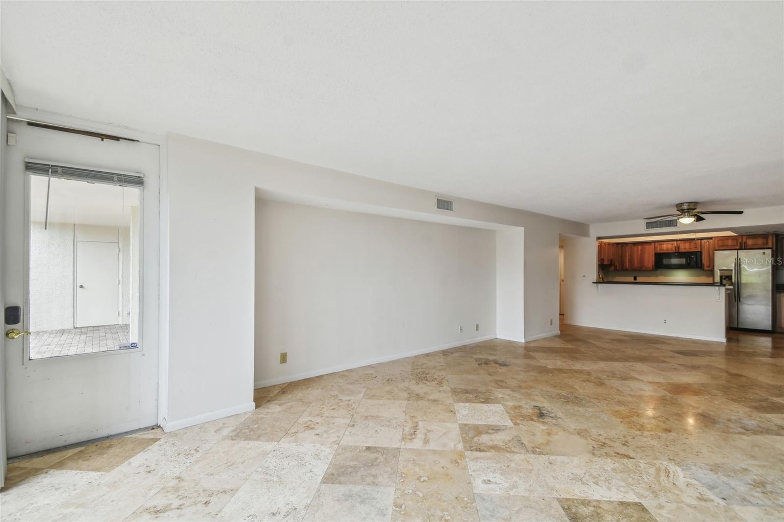 Open living area with patterned tile floors, a glass patio door, and a kitchen with wood cabinets.