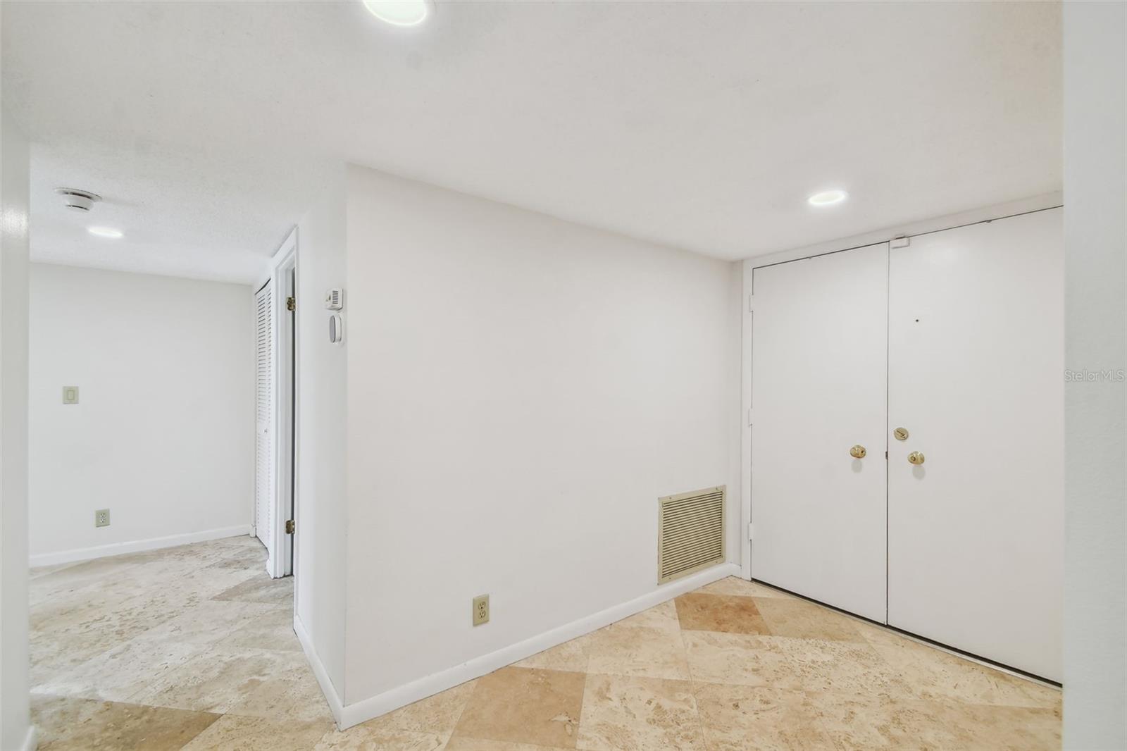Entryway with double entry doors and beige tile flooring.