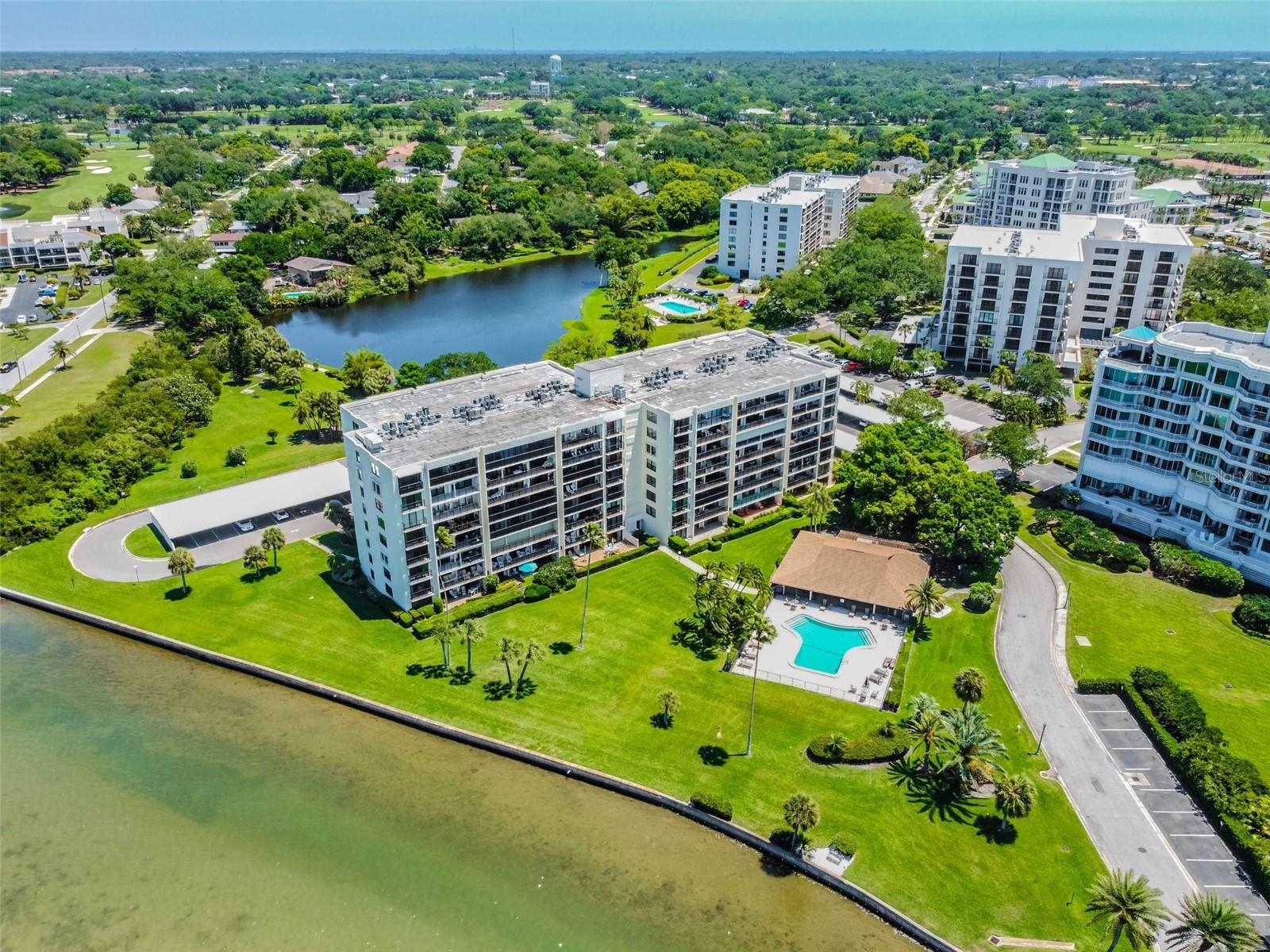 Condominium complex beside a bay, with landscaped grounds, swimming pools, and a lake.