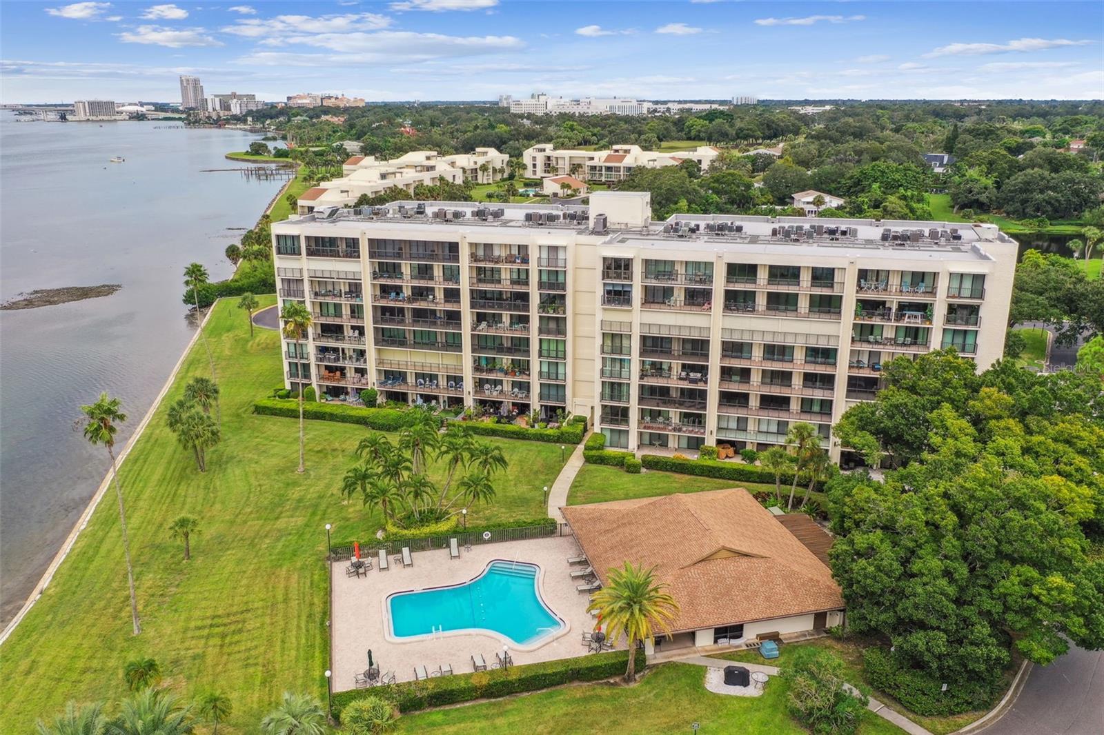 Waterfront condominium with balconies, a swimming pool, and landscaped grounds.