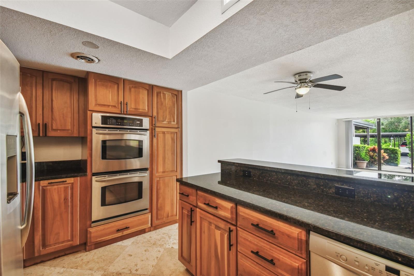 Kitchen with warm wood cabinets, stainless steel appliances, and a dark stone island.