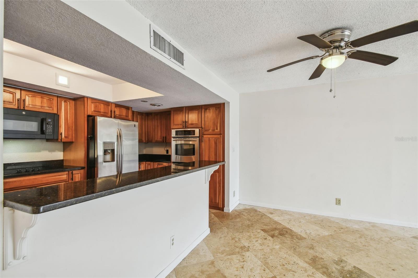 Kitchen and dining area with cherry cabinets, granite breakfast bar, stainless appliances, and tile flooring.