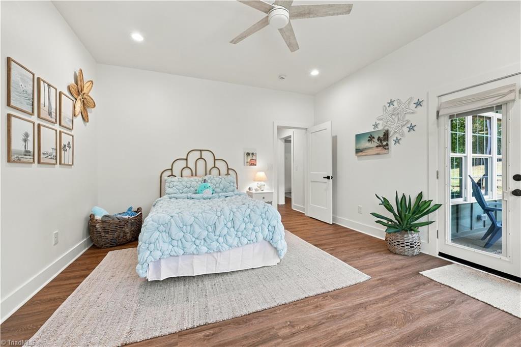 Bedroom with pale blue bedding, coastal wall art, and a glass door to an outdoor seating area.