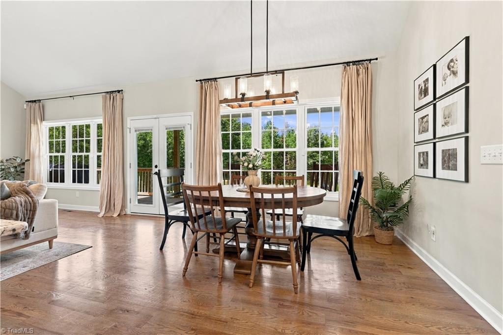 Dining room with hardwood floors, a wooden table, large windows, and French doors.