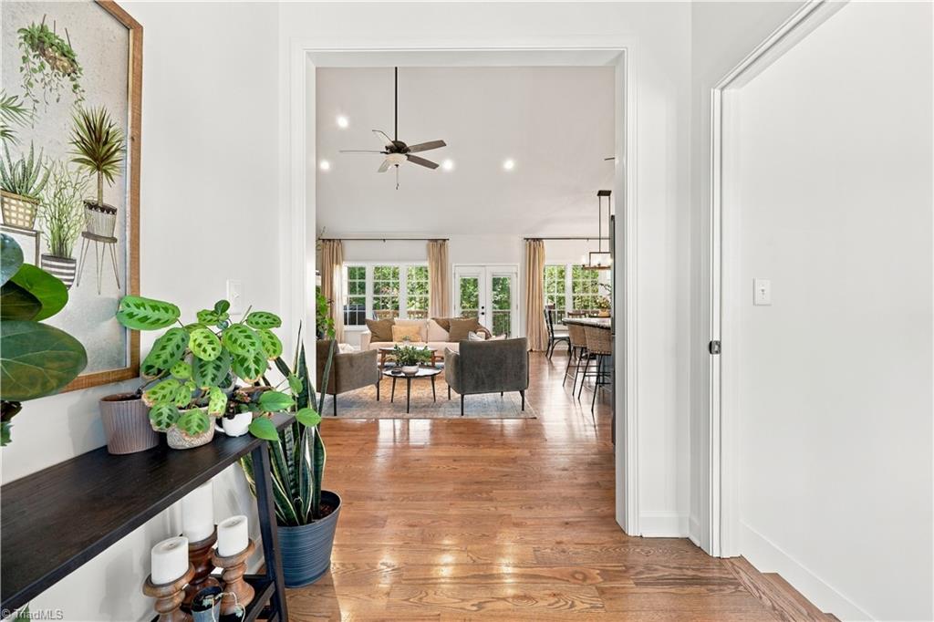 Entry hall with hardwood floors and plants opens into a bright living and dining area.