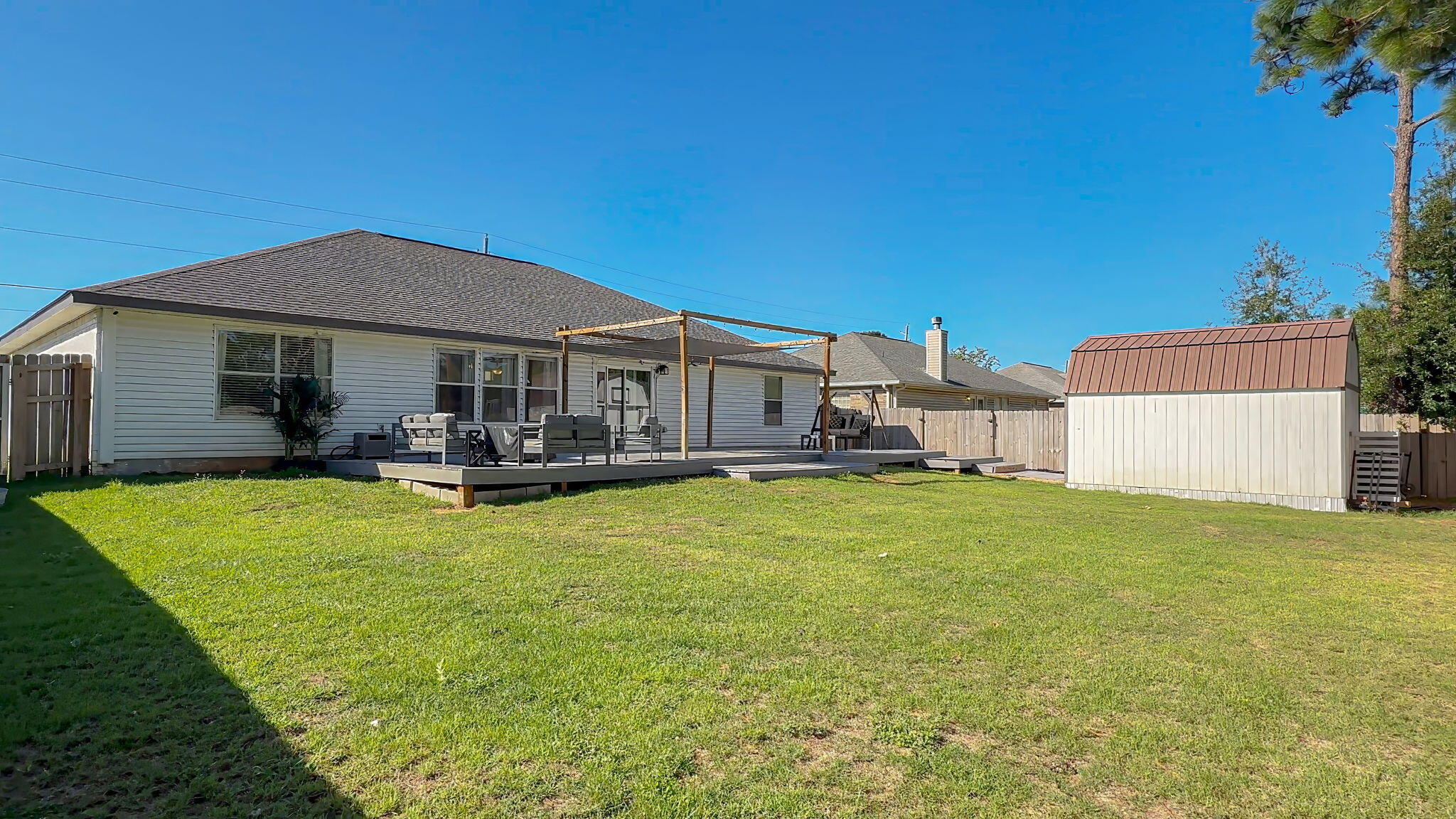 House backyard with a raised deck, pergola, outdoor seating, and detached shed.