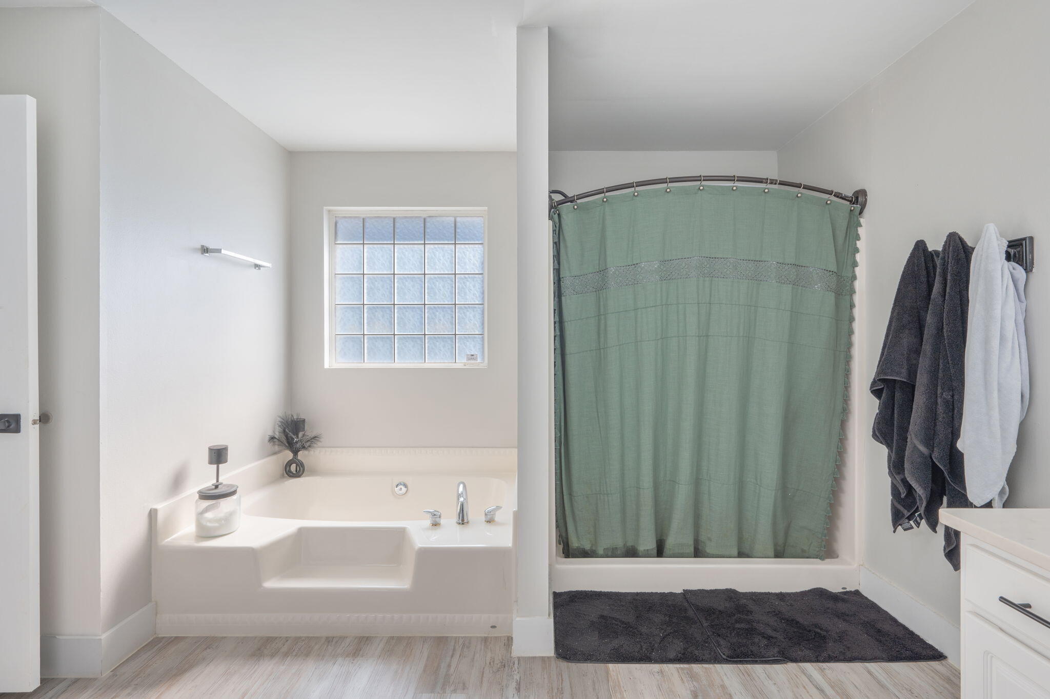 Bathroom with a built-in soaking tub, green shower curtain, and frosted window.