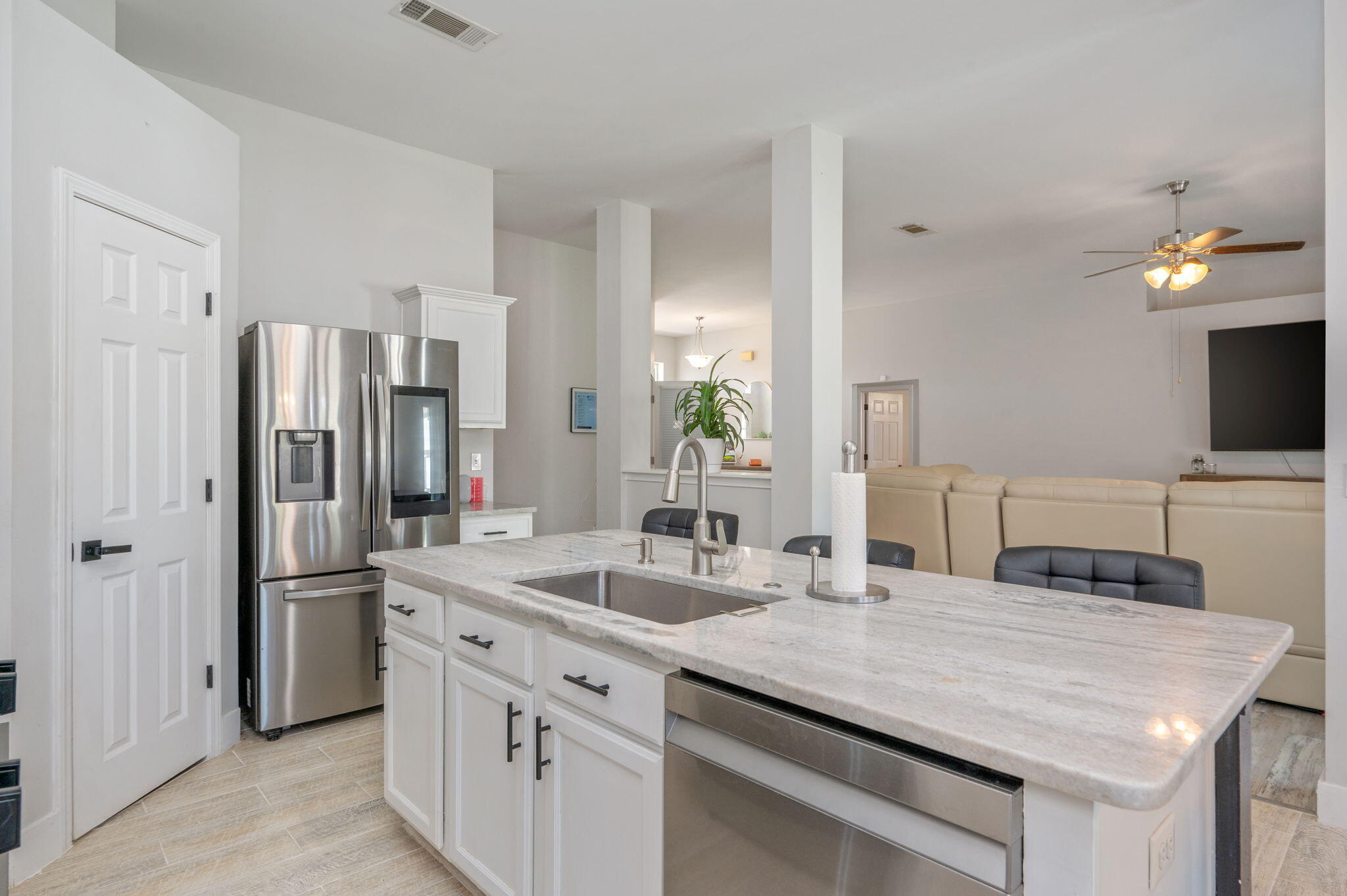 Kitchen with a large stone island, stainless steel appliances, and beige recliners in the adjoining living area.