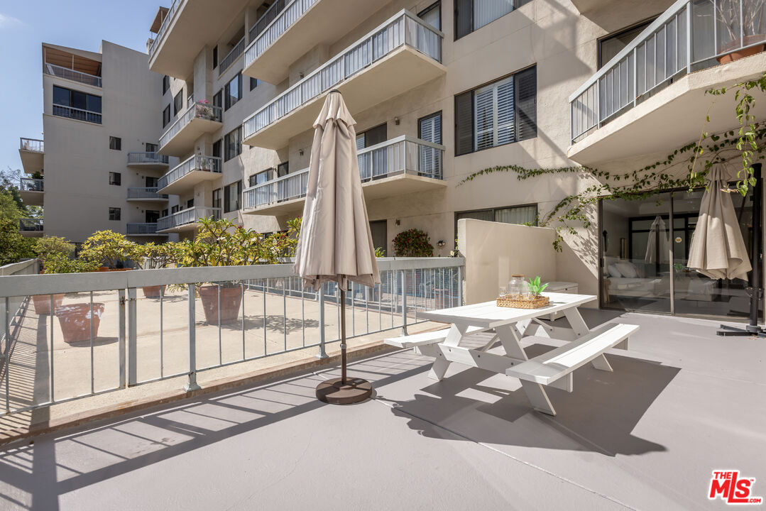 Condominium patio with a white picnic table, closed umbrella, and balconies overlooking the courtyard.