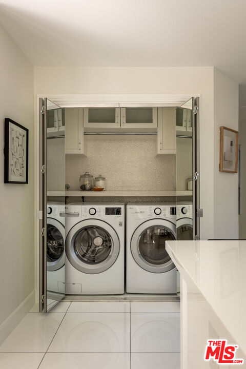 Laundry room with front-loading washer and dryer behind mirrored folding doors.