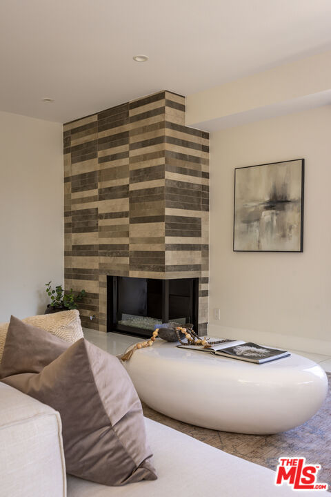 Living room with a banded stone fireplace, light sofa, and sculptural white coffee table.