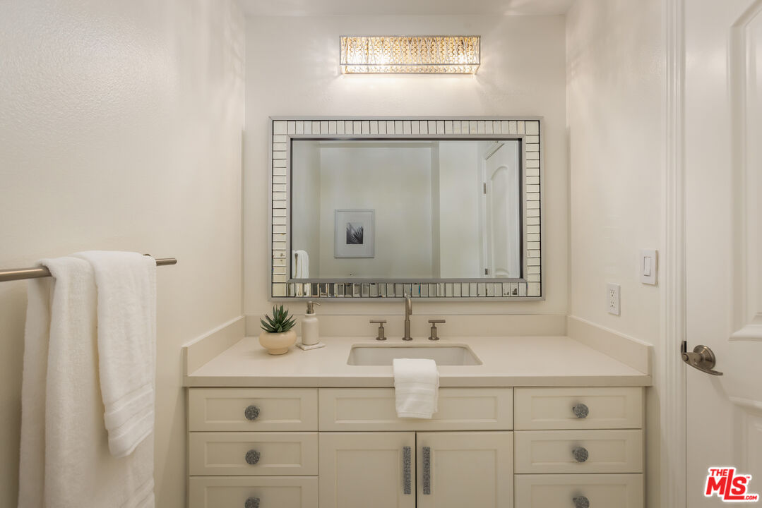Bathroom vanity with a large framed mirror, white sink, and cream cabinetry.