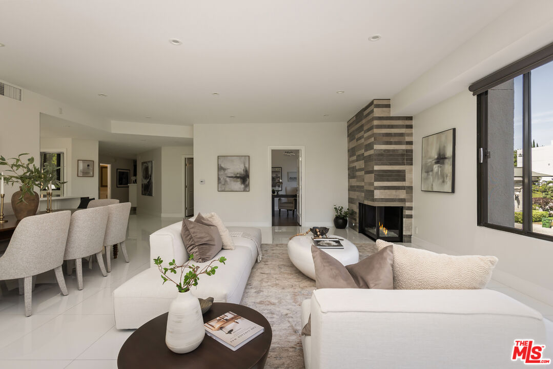 Staged living room with white seating, a striped stone fireplace, and large windows.