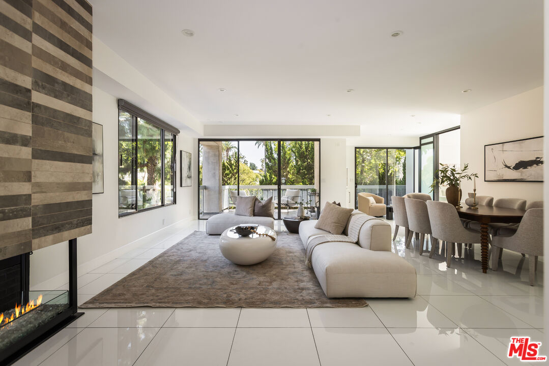 Modern condo living room with a white sectional, stone fireplace wall, and large windows overlooking trees.