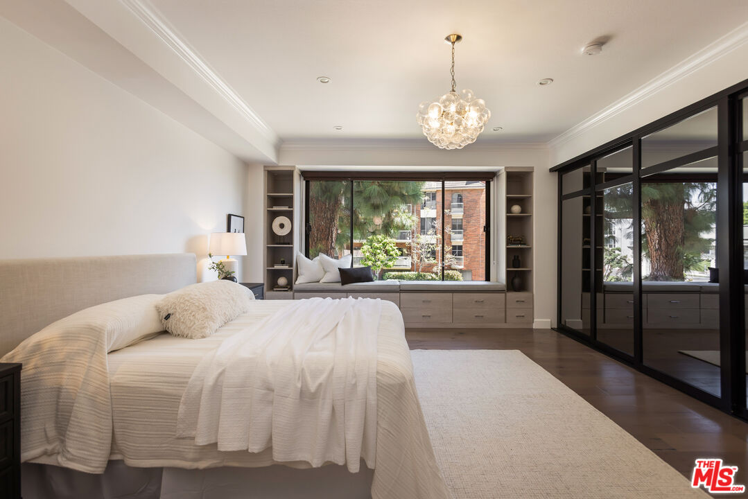 Bedroom with a built-in window seat, large window, and black-framed mirrored closet doors.