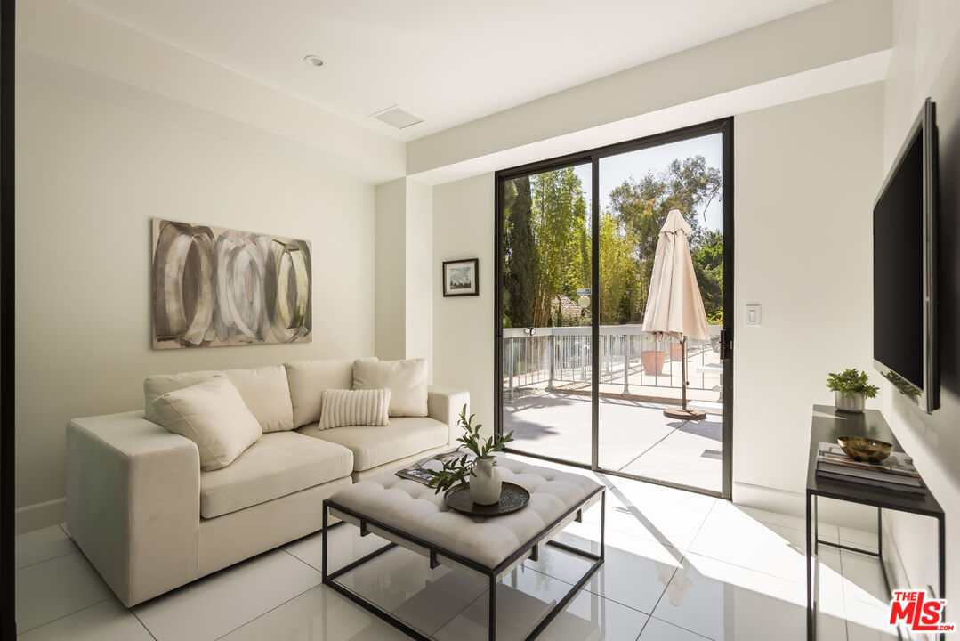 Living room with a white sofa and coffee table beside sliding doors to a sunny patio.