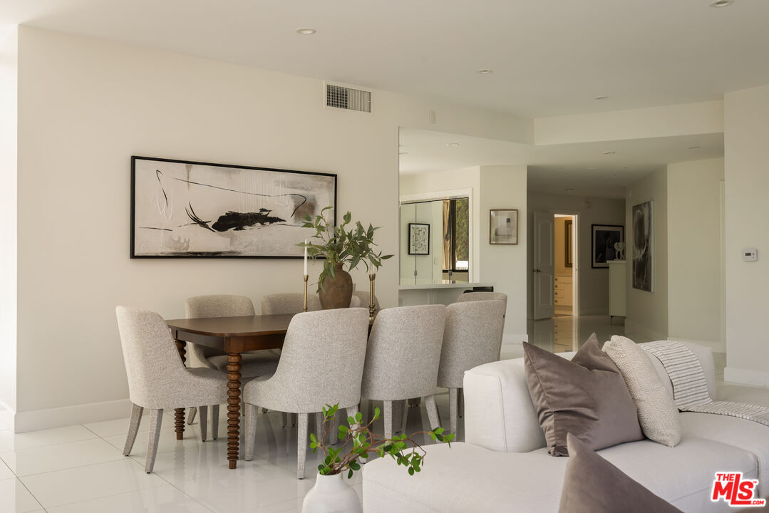 Open-plan living and dining area with white seating, a wood table, and abstract wall art.