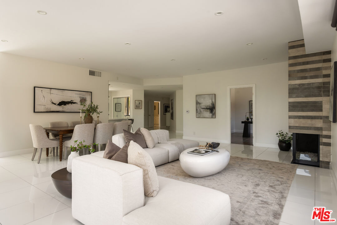 Open-plan living and dining room with a light sectional and striped-tile fireplace.