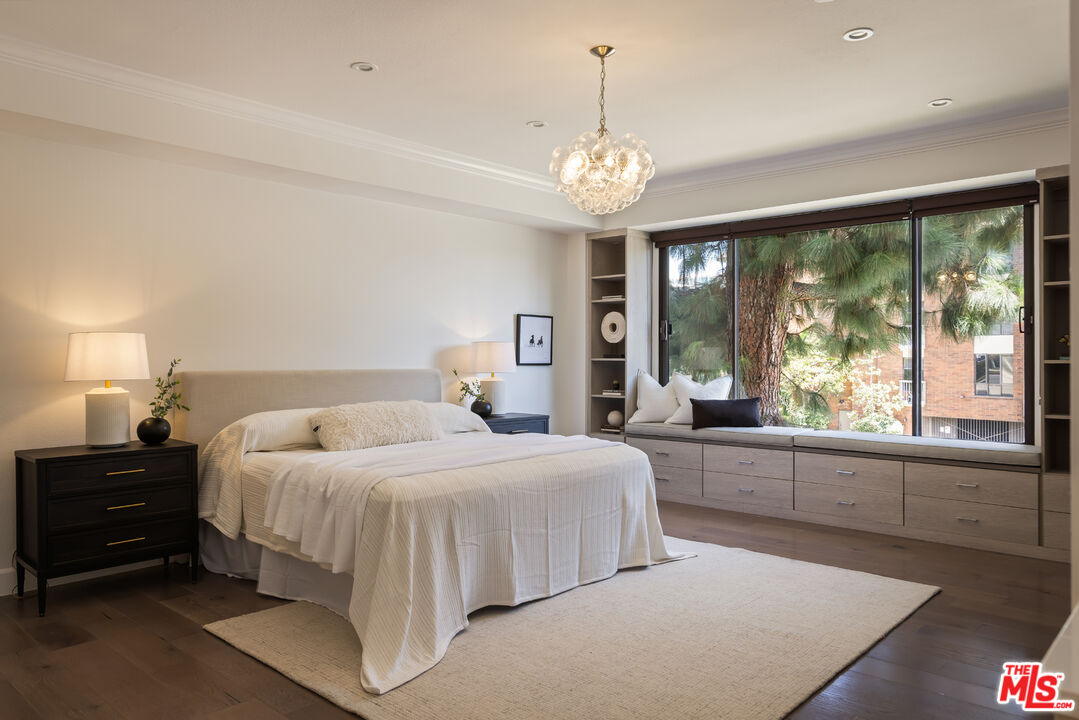 Staged bedroom with a king-size bed and a large window overlooking trees.