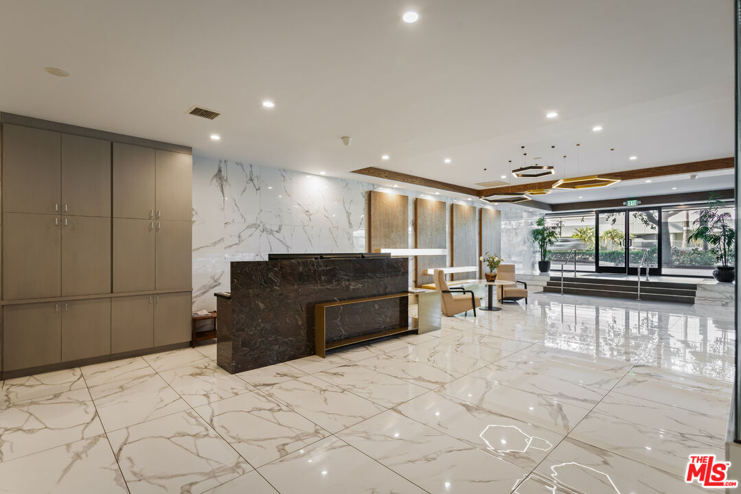 Modern lobby with a dark marble reception desk and polished marble-patterned floors.