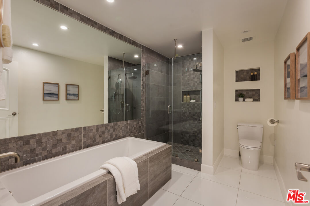 Bathroom with a tiled soaking tub, glass-enclosed walk-in shower, and built-in wall niches.