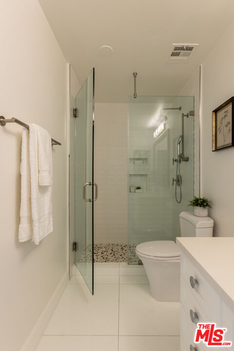 Bathroom with a glass-enclosed shower, built-in niches, and white vanity.