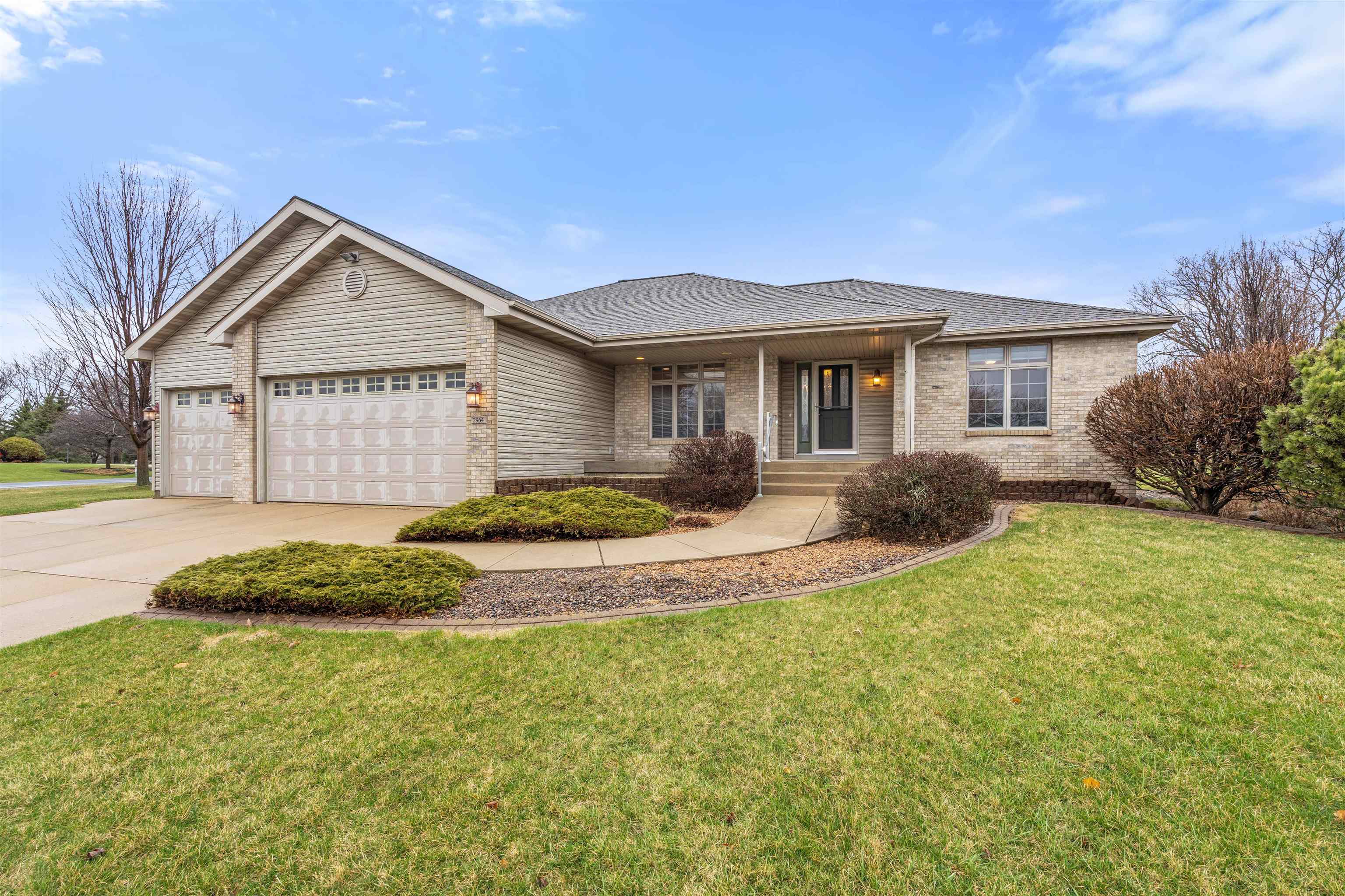 Single-story brick-and-siding home with two garage doors, a covered entry, and landscaped front lawn.