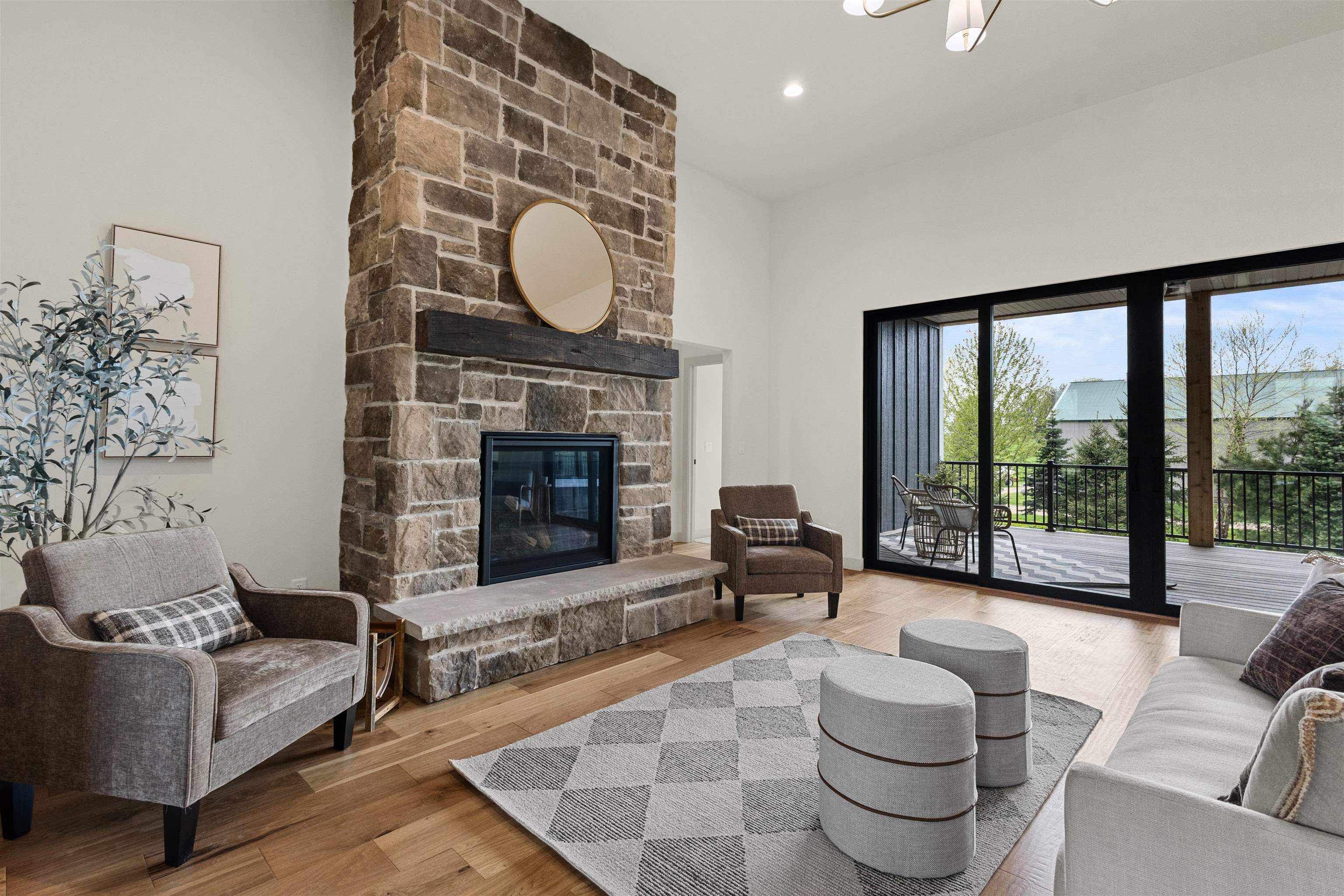Living room with a tall stone fireplace, gray seating, and sliding doors to a covered deck.