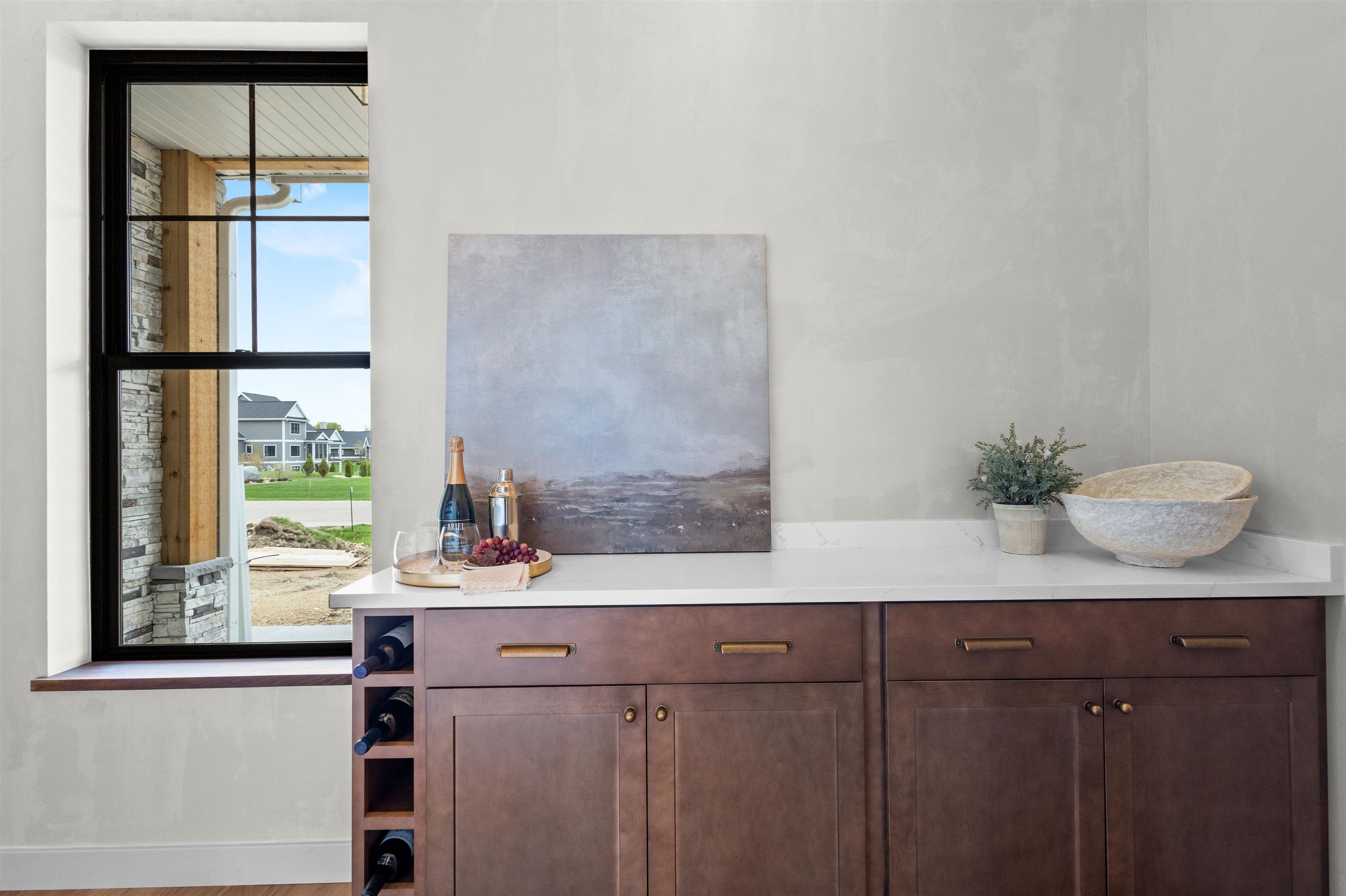 Wine bar with dark wood cabinetry, built-in bottle storage, and a large window overlooking the neighborhood.