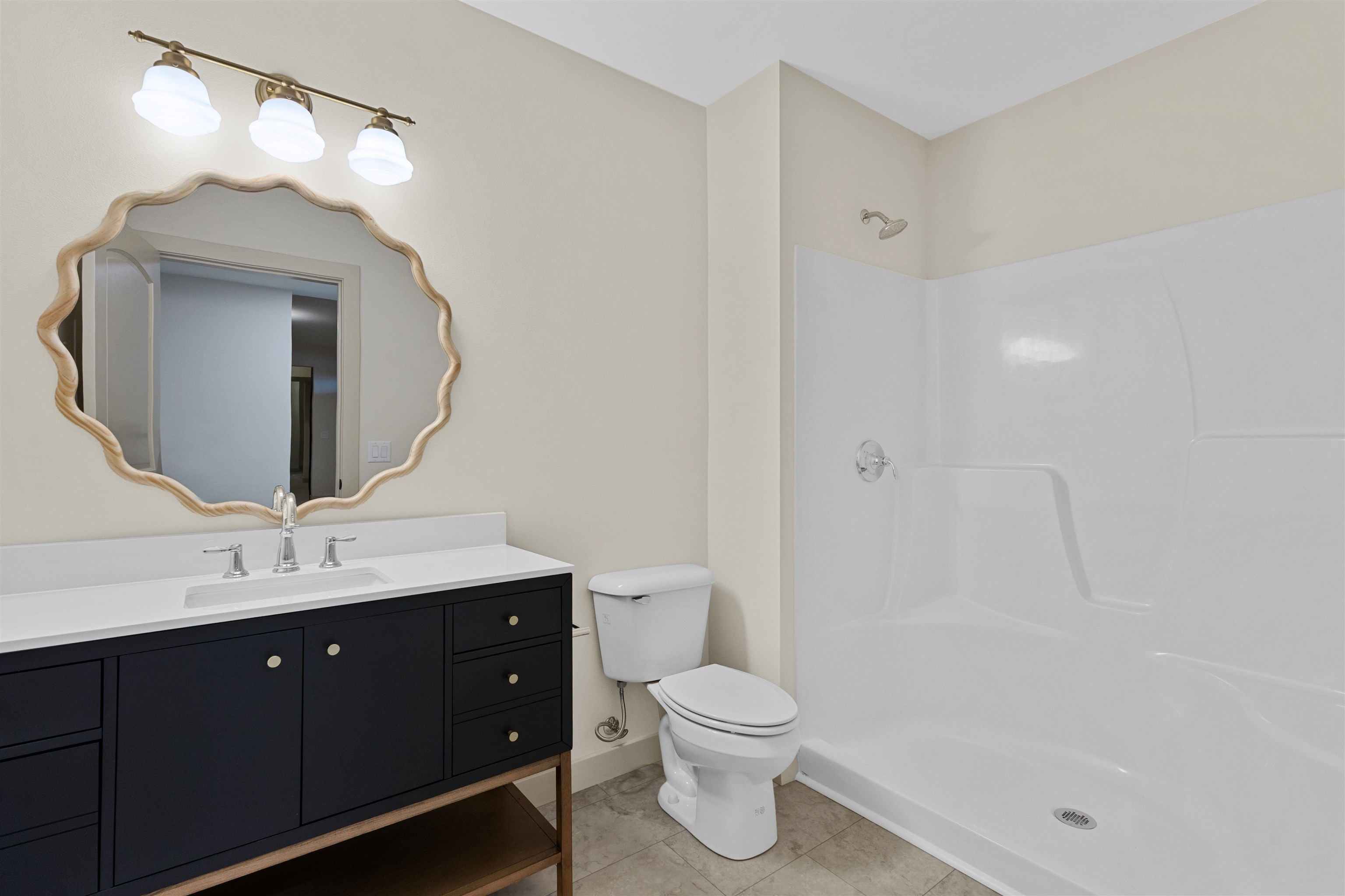 Bathroom with a dark vanity, wavy wood-framed mirror, toilet, and white tub-shower.