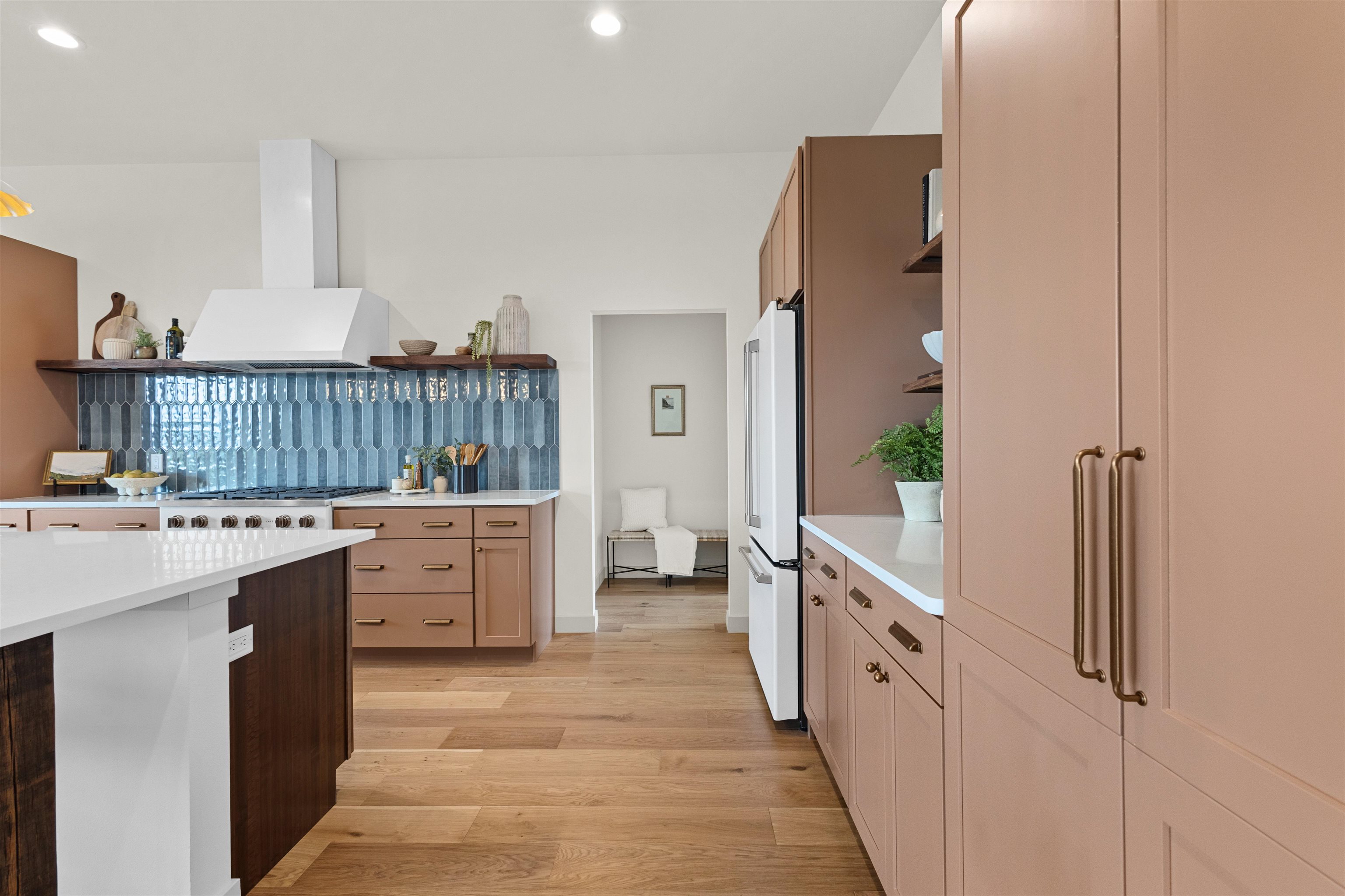 Kitchen with dusty rose cabinets, blue-gray tile backsplash, and a large white island.