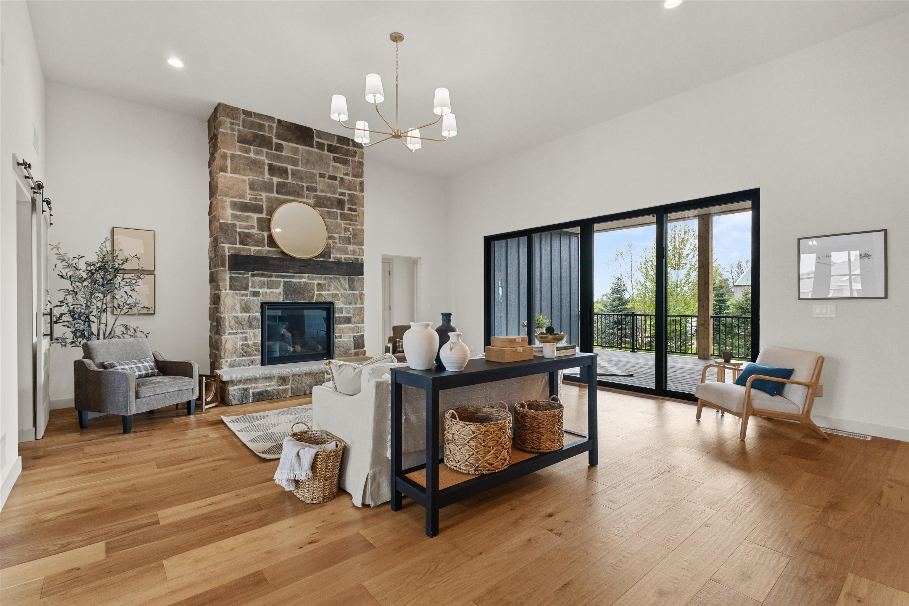 Living room with a tall stone fireplace and sliding doors opening onto a covered deck.