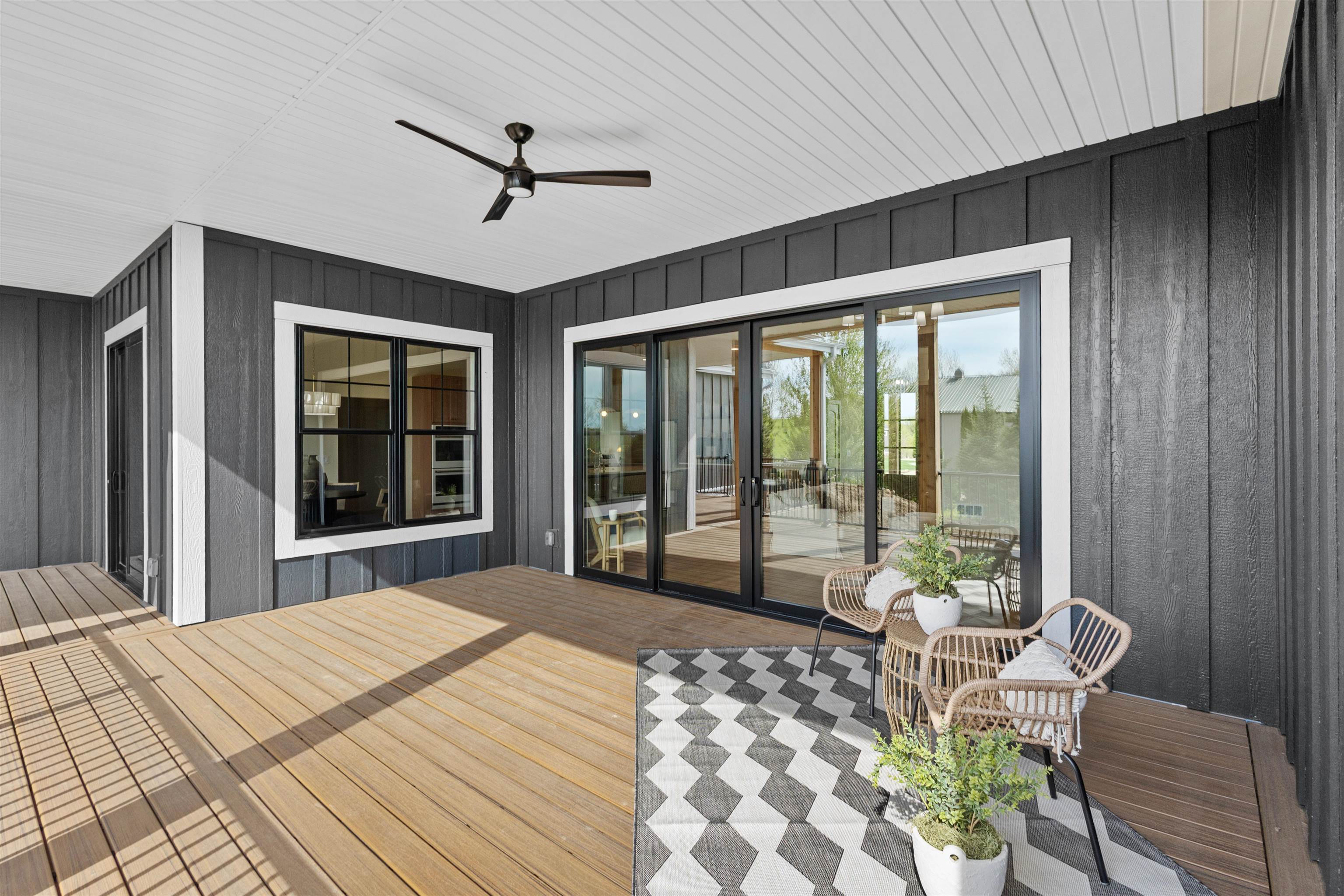 Covered deck with sliding glass doors, wicker seating, and a ceiling fan.