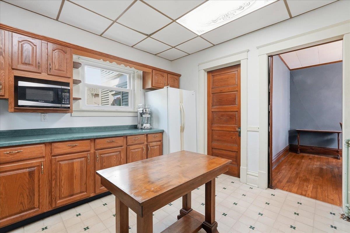 Kitchen with wood cabinets, green countertops, and a large wooden worktable.