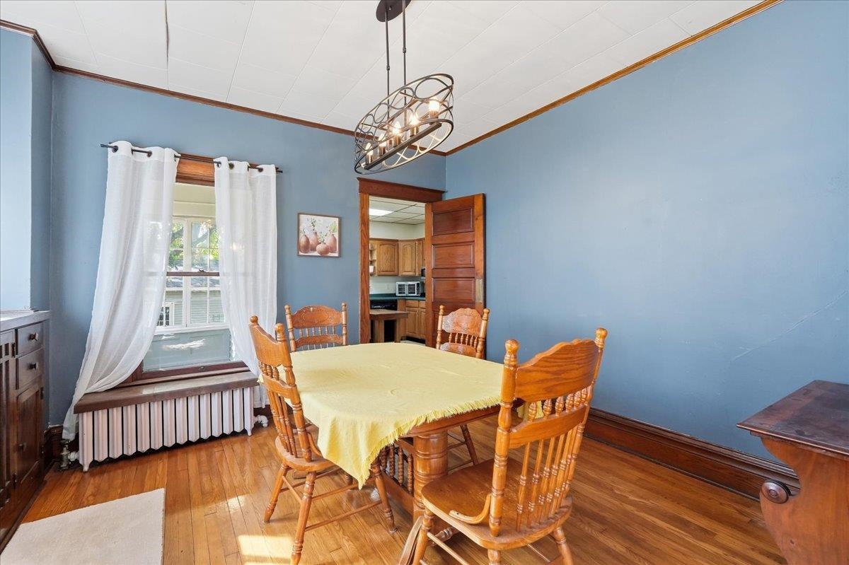 Dining room with blue walls, a wooden dining set, hardwood floors, and a curtained window.