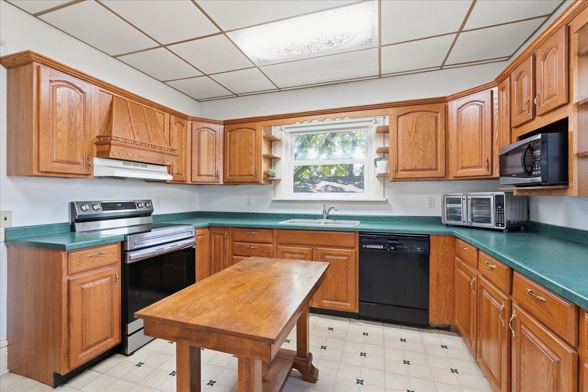 Kitchen with wood cabinets, teal countertops, and a wooden worktable.