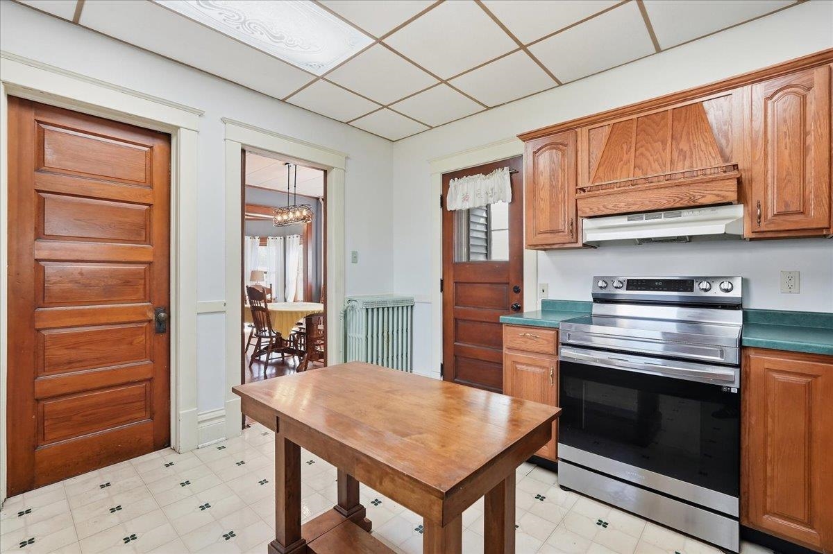 Kitchen with warm wood cabinets, a stainless steel range, and a central wooden table.