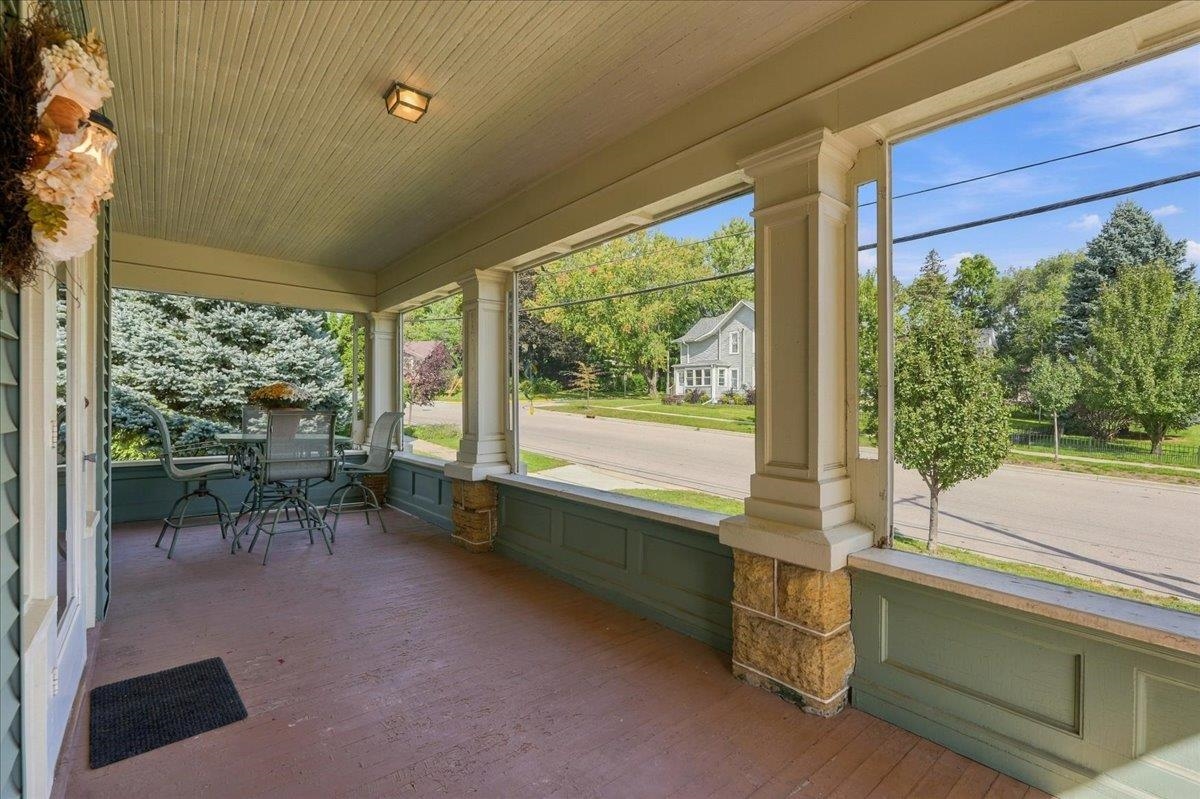 Covered front porch with stone-based columns and patio dining set overlooking a residential street.