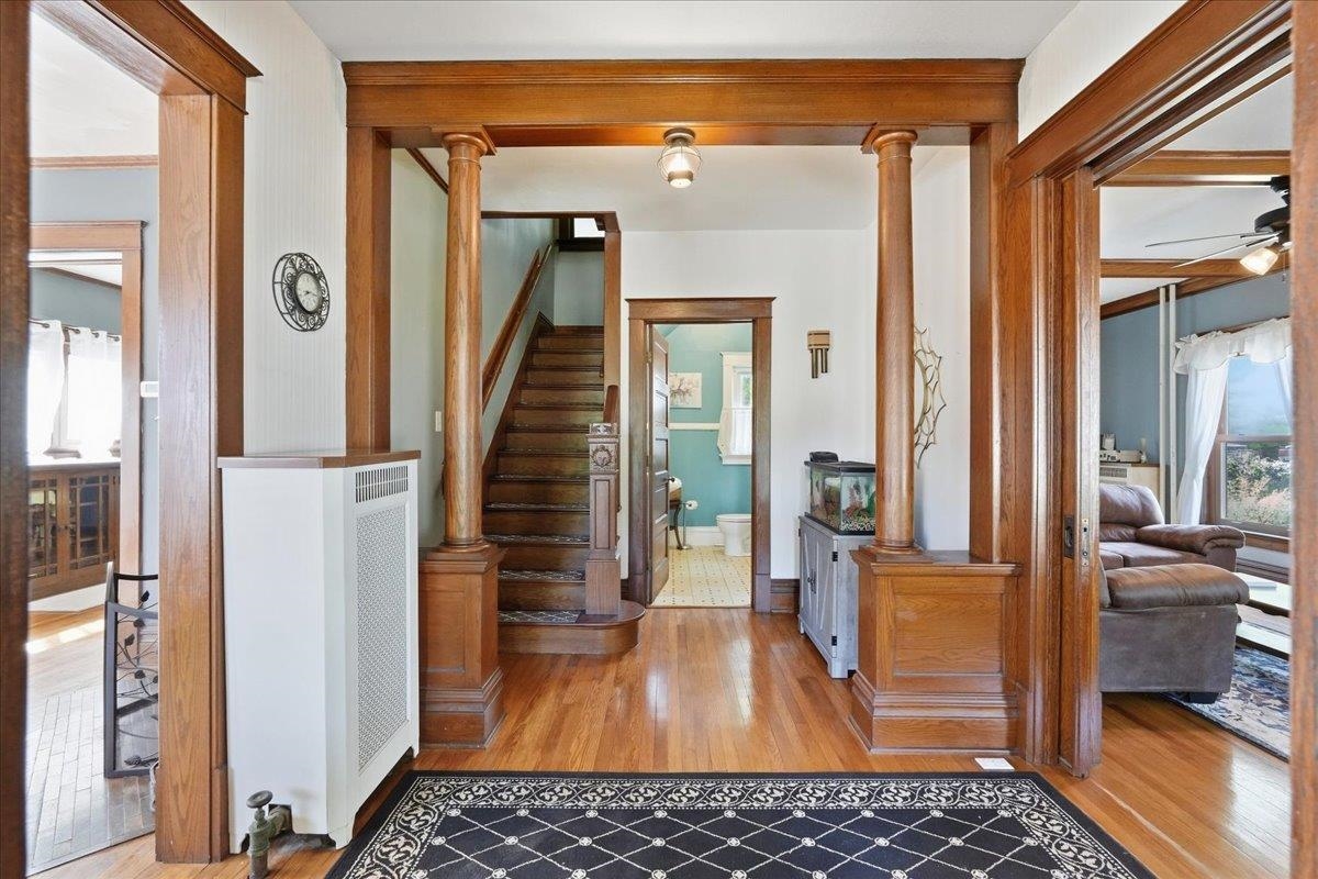Foyer with ornate wood columns, polished floors, and a staircase.