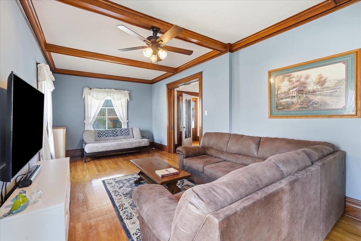Living room with a large sectional sofa, hardwood floors, and a wood-trimmed tray ceiling.