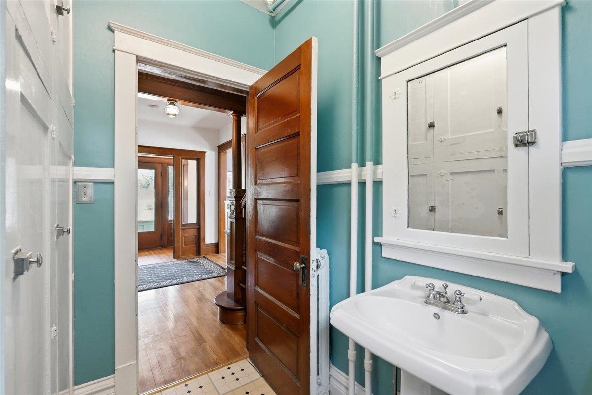 Bathroom with turquoise walls, a white pedestal sink, and an open wood door to the hallway.