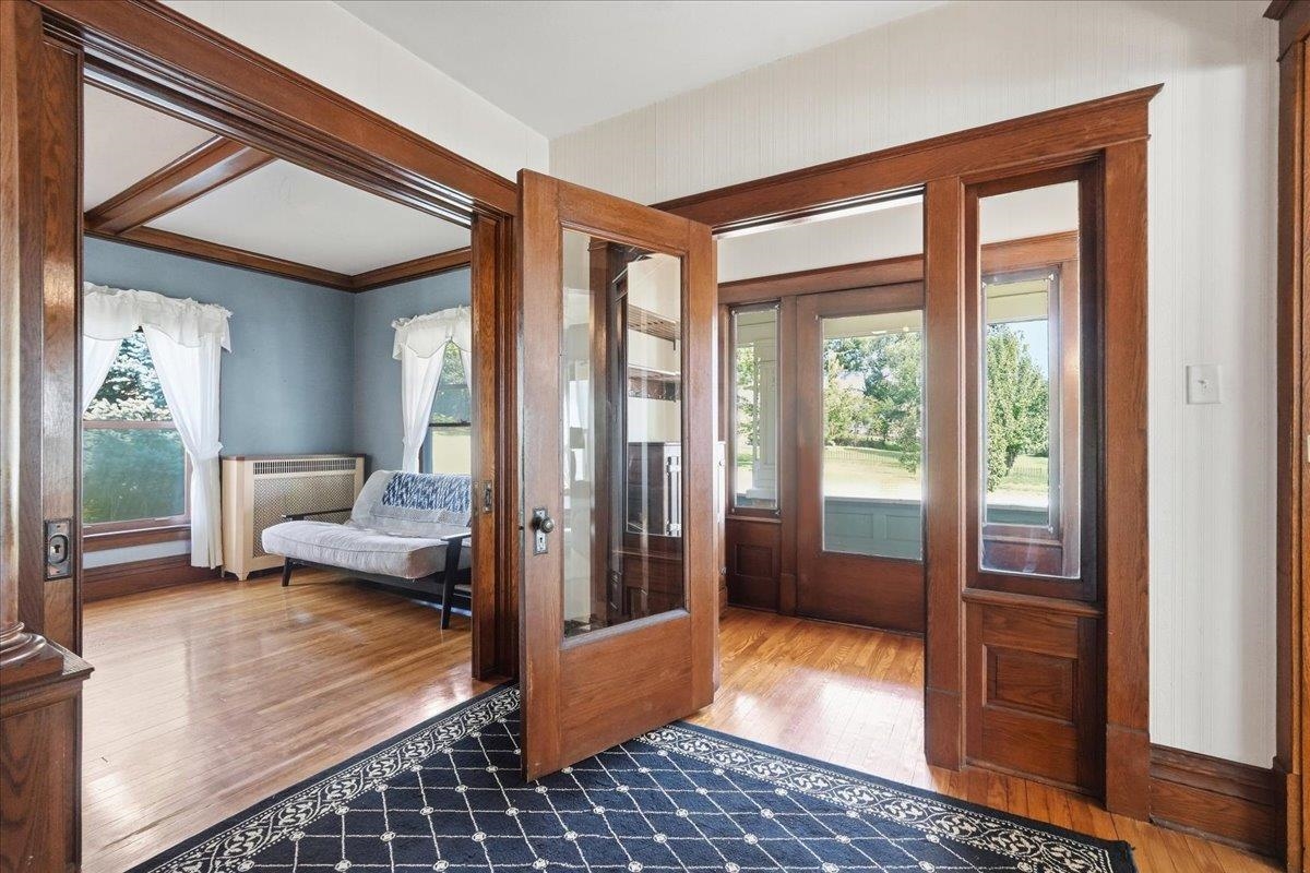 Entry foyer with ornate wood trim and glass doors opening to a blue sitting room.