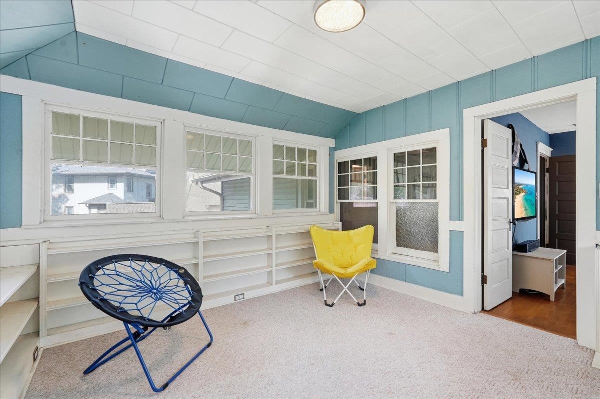 Sunroom with blue paneled walls, white built-in shelving, several windows, and two folding chairs.