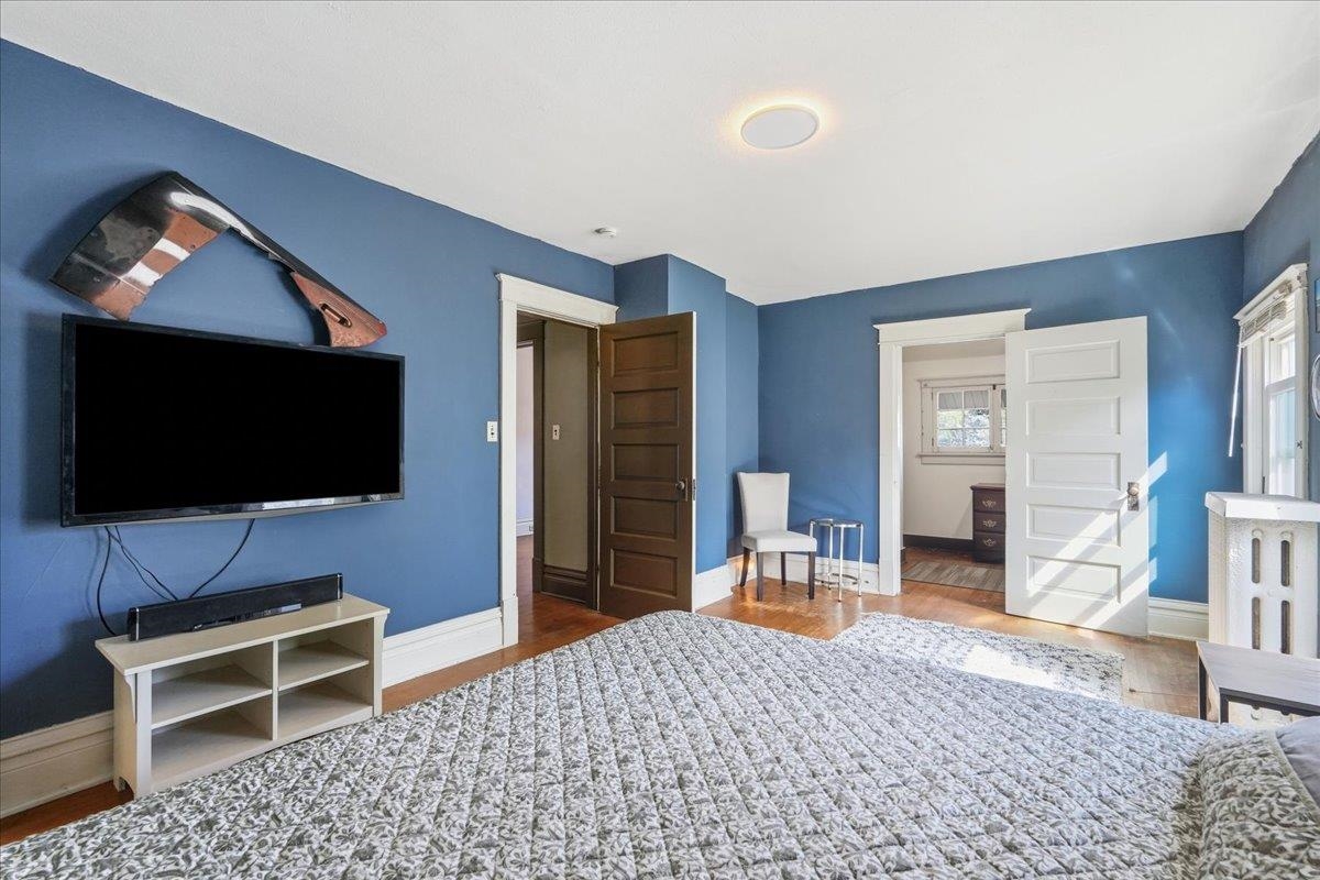 Bedroom with blue walls, patterned bedspread, wall-mounted television, and open doorways to adjoining rooms.