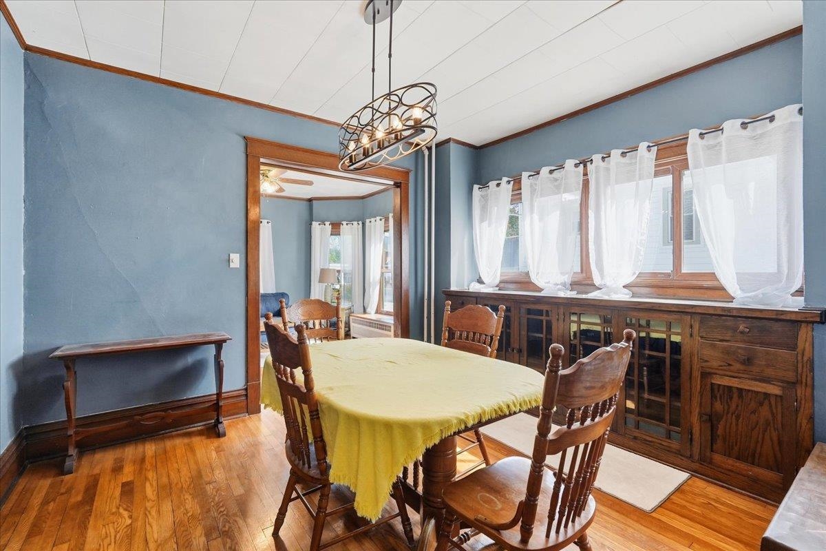 Dining room with a wooden table, built-in cabinetry, blue walls, and large curtained windows.