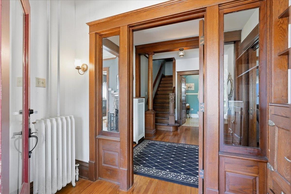 Entryway framing a staircase, with rich wood trim, hardwood floors, and a patterned rug.