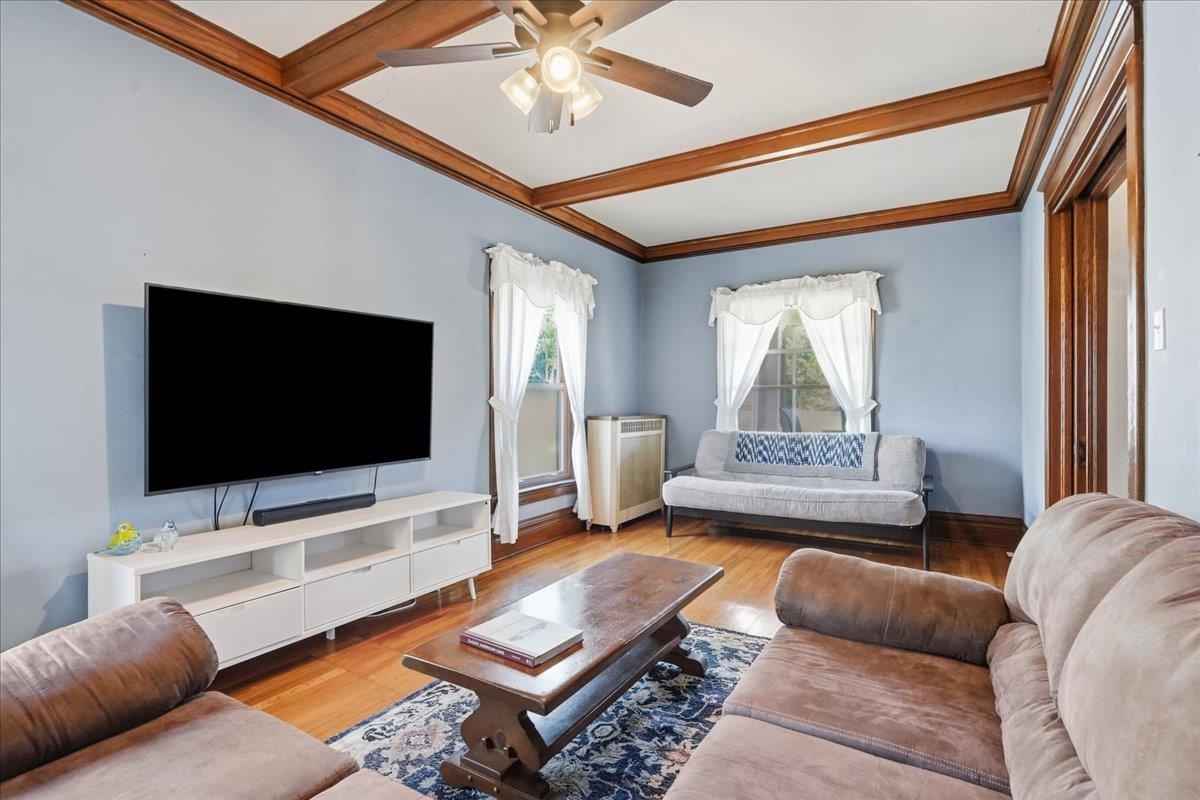 Living room with a wood-beamed ceiling, hardwood floors, and seating arranged around a coffee table.