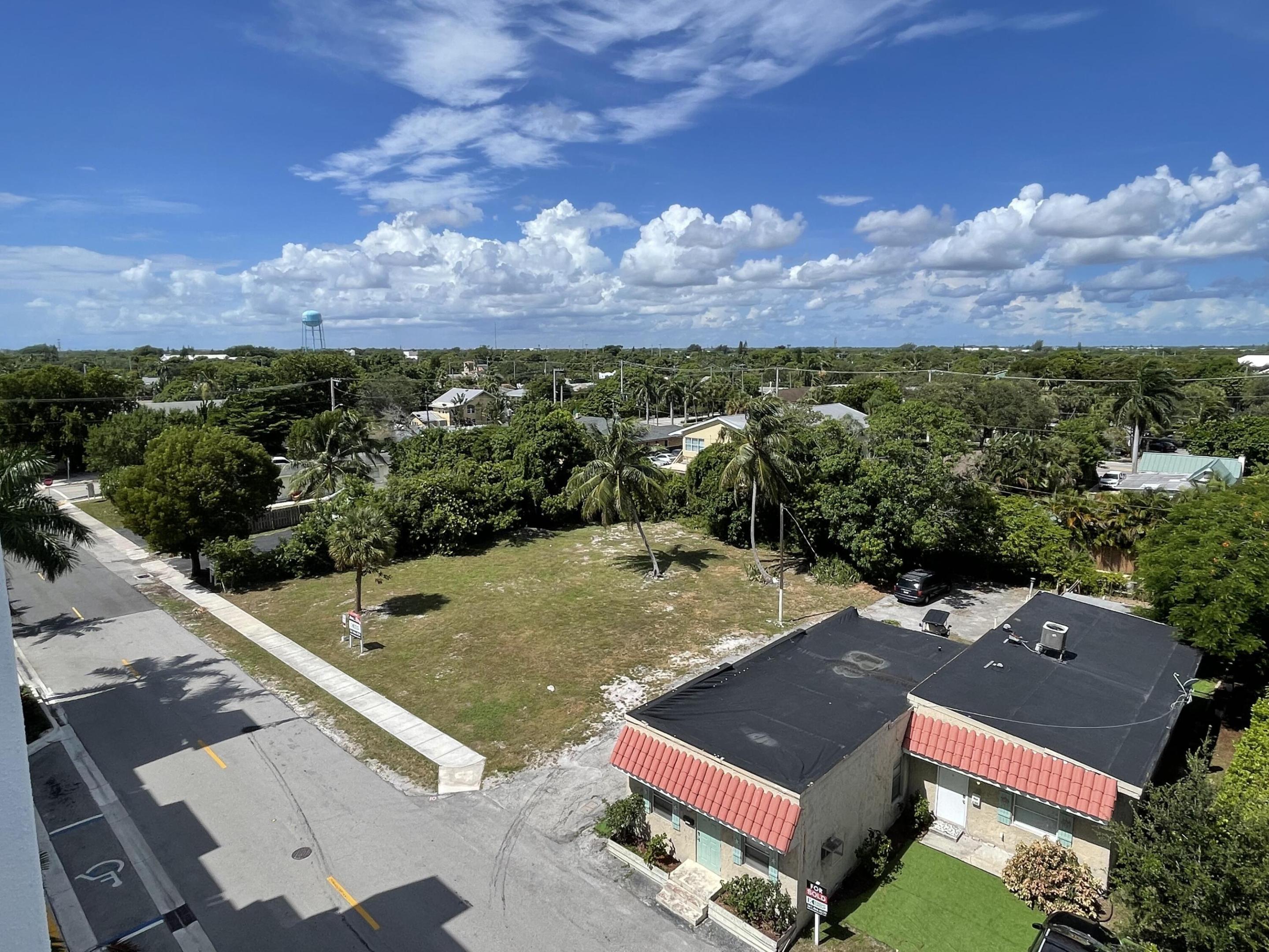 Aerial view of a vacant lot and surrounding palm-lined neighborhood.