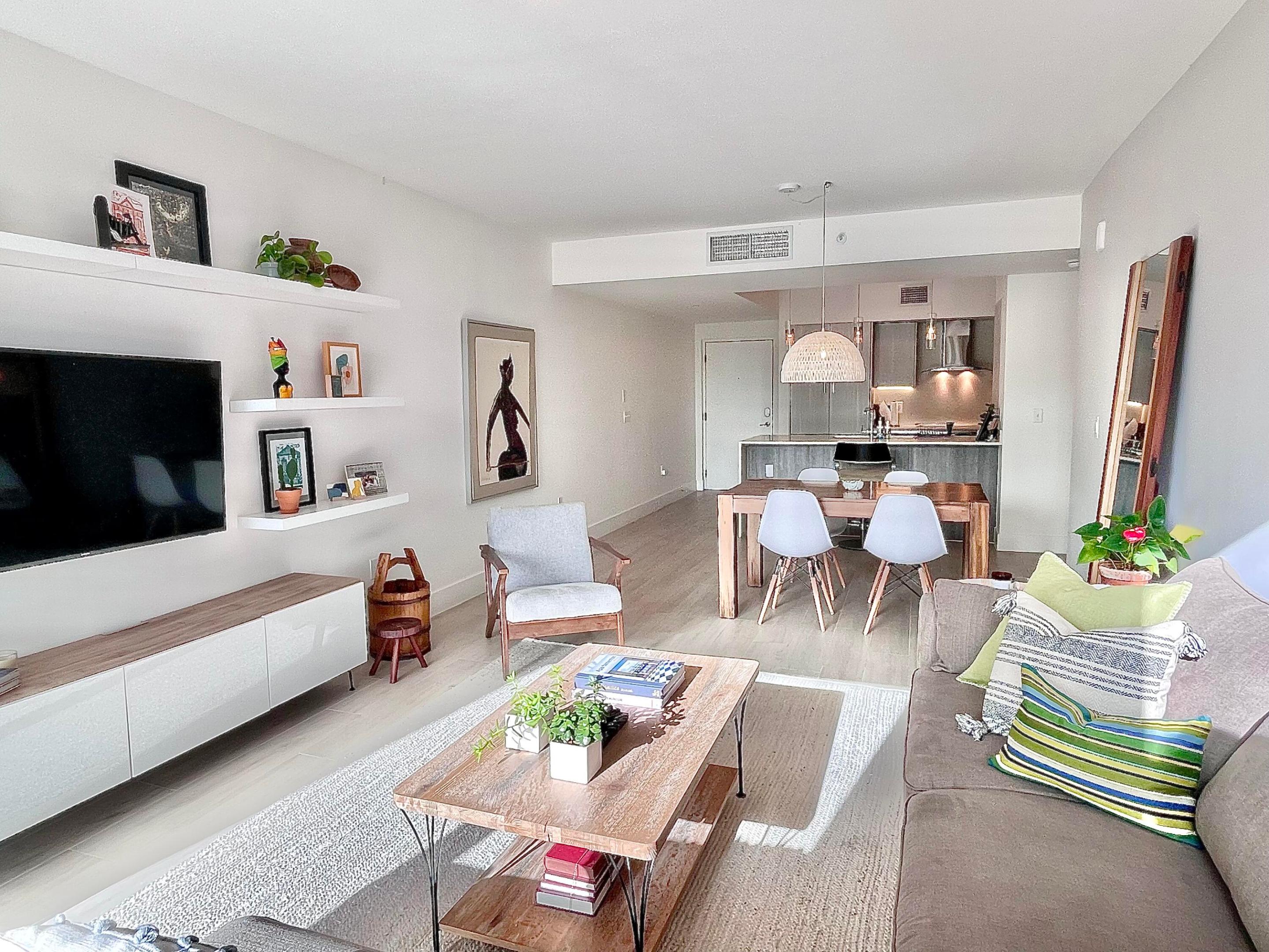 Open-plan living room with a gray sofa, wood coffee table, and dining area beside the kitchen.